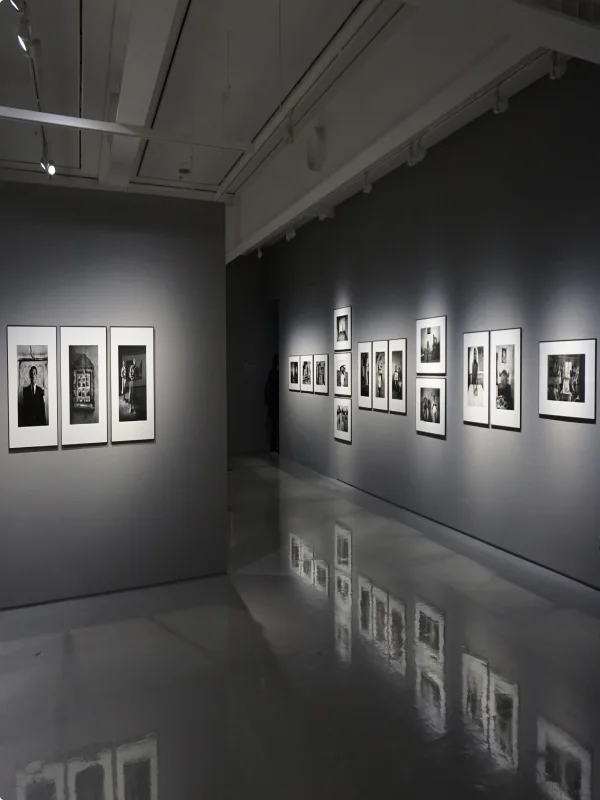 Eine Kunst-Ausstellung von Schwarz-Weiß-Fotografien in einem dunklen Raum.
