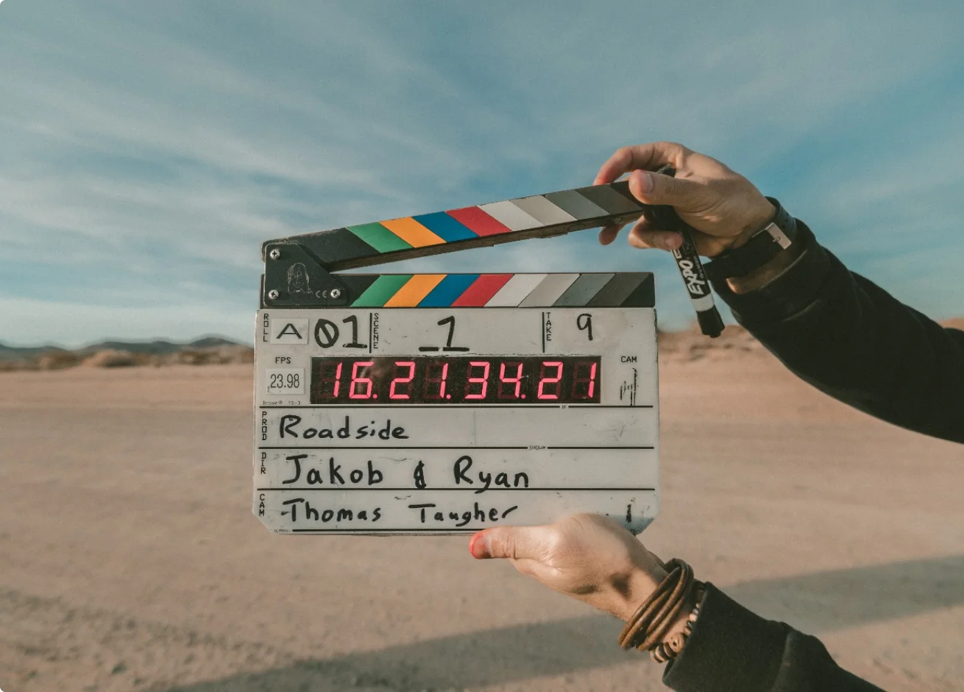Ein Crew-Mitglied hält eine Klappe an einem Filmset in der Wüste hoch.