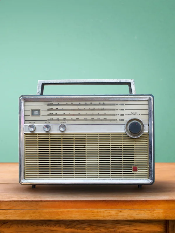 Ein altes Radio auf einem Holztisch vor einer grünen Wand.