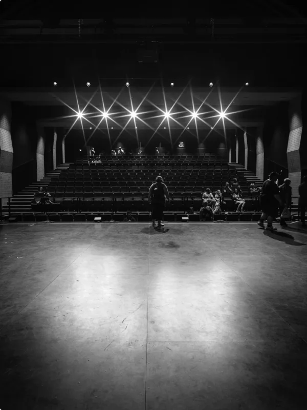 Schauspieler auf der Bühne eines leeren Theater-Auditoriums.