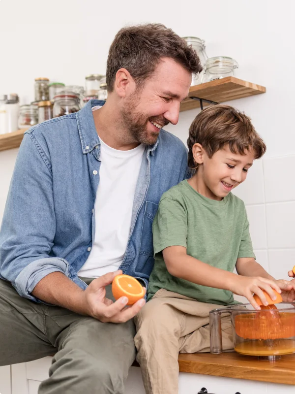 Vater und Sohn bereiten zusammen Orangensaft zu