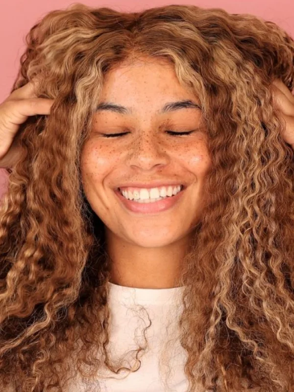 Lachende Frau mit lockigem Haar und Sommersprossen