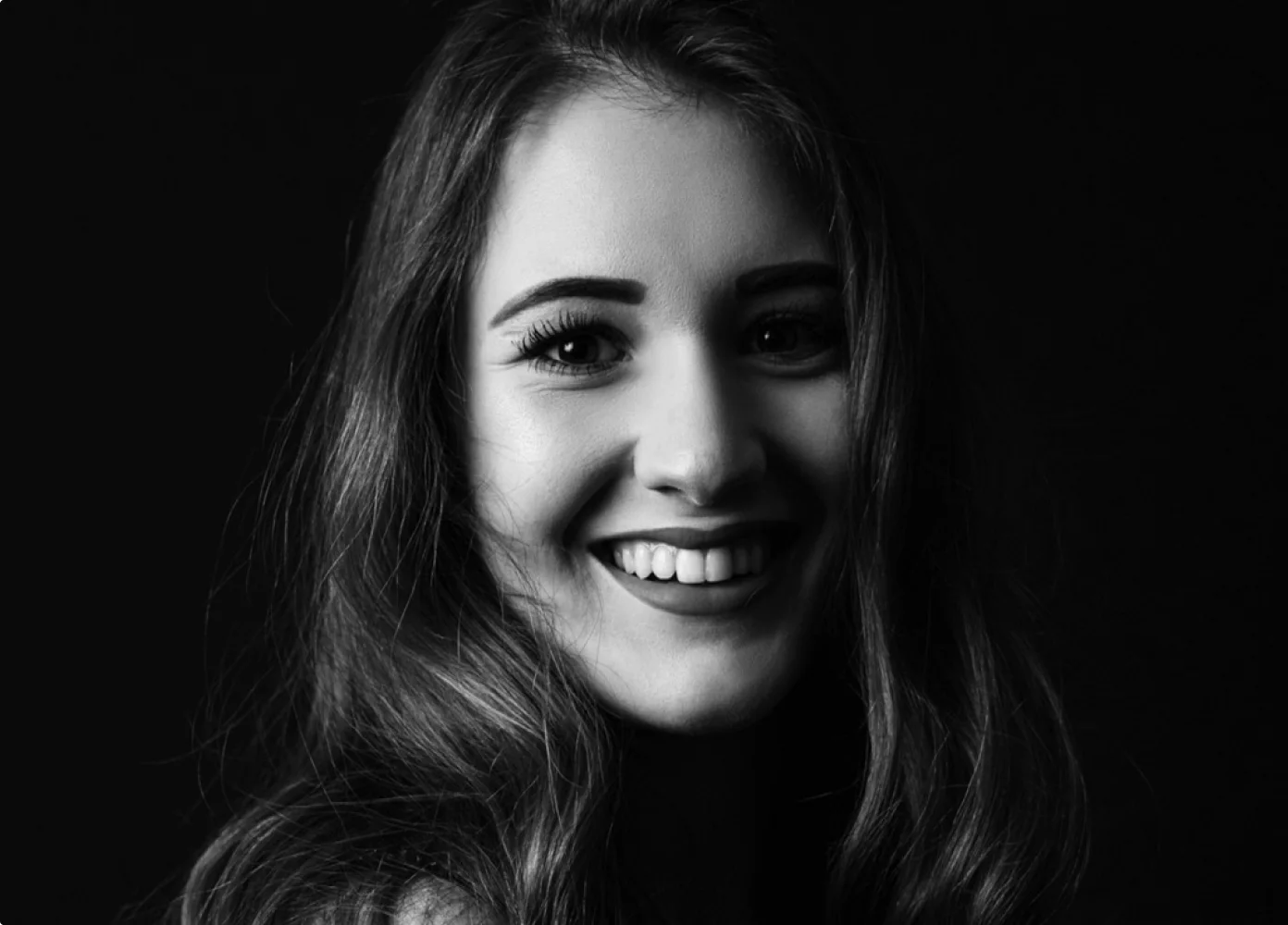 Lächelnde Frau mit langen Haaren in Schwarz-Weiß-Fotografie