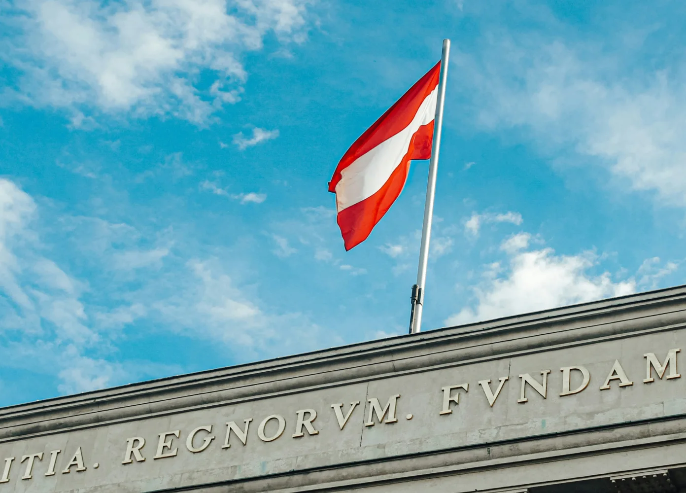 Österreichische Flagge weht im Wind vor blauem Himmel