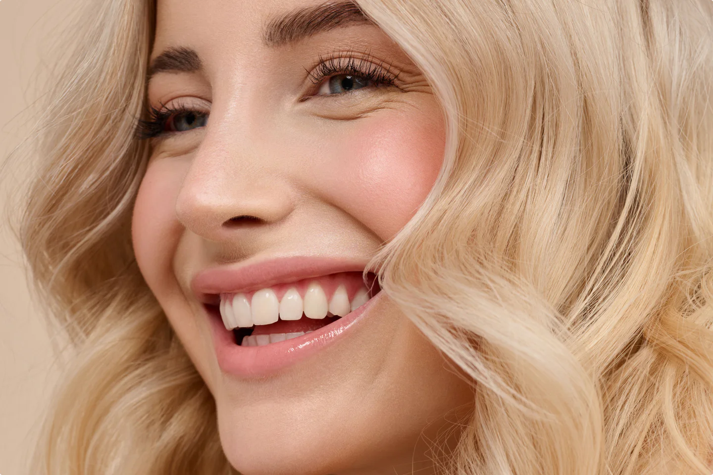 Nahaufnahme einer lächelnden blonden Models mit welligem Haar.