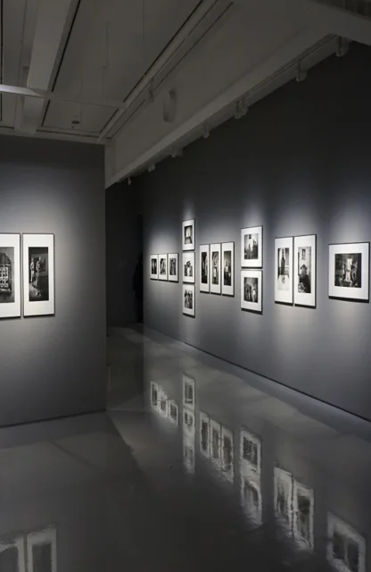 Eine Kunst-Ausstellung von Schwarz-Weiß-Fotografien in einem dunklen Raum.