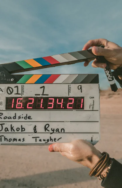 Ein Crew-Mitglied hält eine Klappe an einem Filmset in der Wüste hoch.
