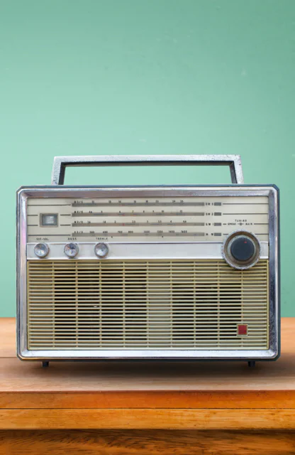 Ein altes Radio auf einem Holztisch vor einer grünen Wand.
