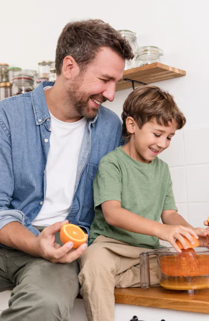 Vater und Sohn bereiten zusammen Orangensaft zu