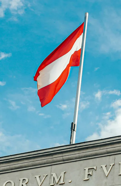 Österreichische Flagge weht im Wind vor blauem Himmel
